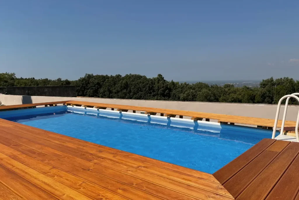 DIY fiberglass pool kit with a wooden deck, offering a stunning elevated view and crystal-clear water.