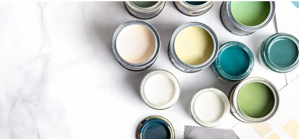 An assortment of open paint cans in shades of white, beige, green, and blue, perfect for use as concrete pool paint.