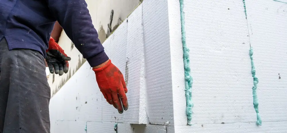 Worker installing EPS foam panels for EPS pool installation using adhesive foam.