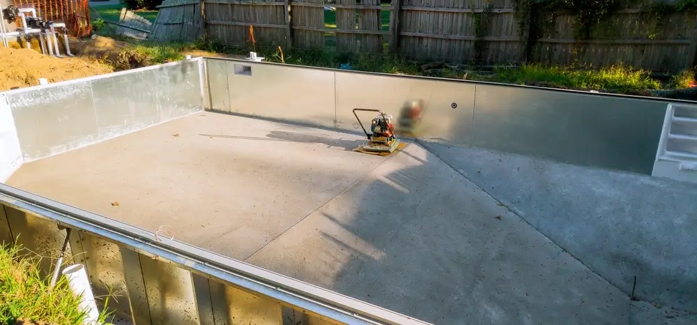 Installation process of a fiberglass pool shell by leading fiberglass pool manufacturers, featuring a partially constructed pool.