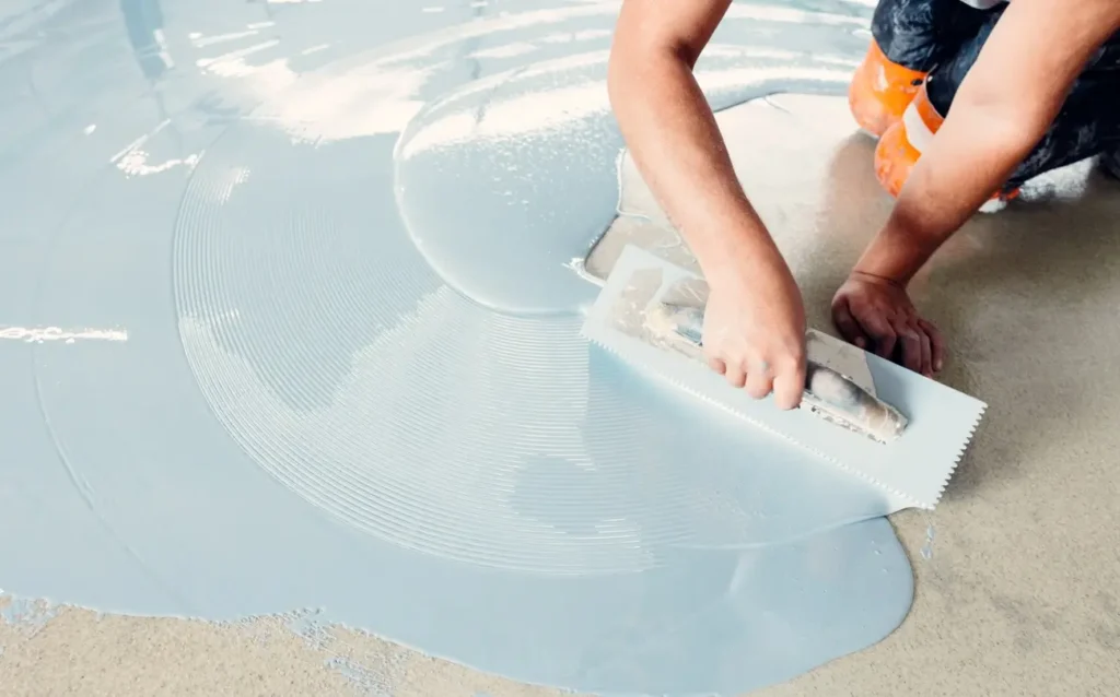 Close-up of a worker repairing a fiberglass pool gelcoat using a notched trowel to apply a smooth coating.