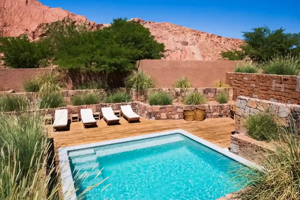 A fiberglass pool in Houston surrounded by wooden decking and a tranquil desert-inspired landscape.