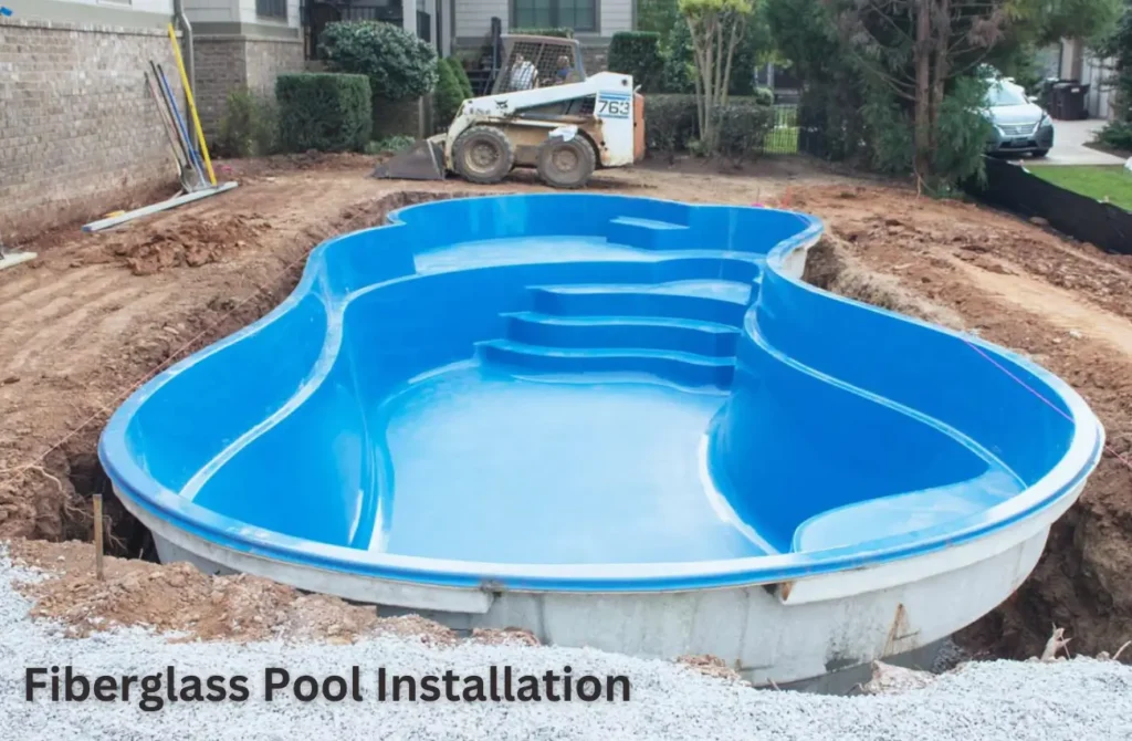 Installation of a fiberglass pool on a sloped yard with a vibrant blue interior.