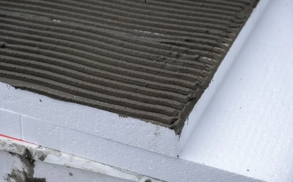 Close-up view of EPS pool (expanded polystyrene) insulation sheets with adhesive grooves, used in pool installation.