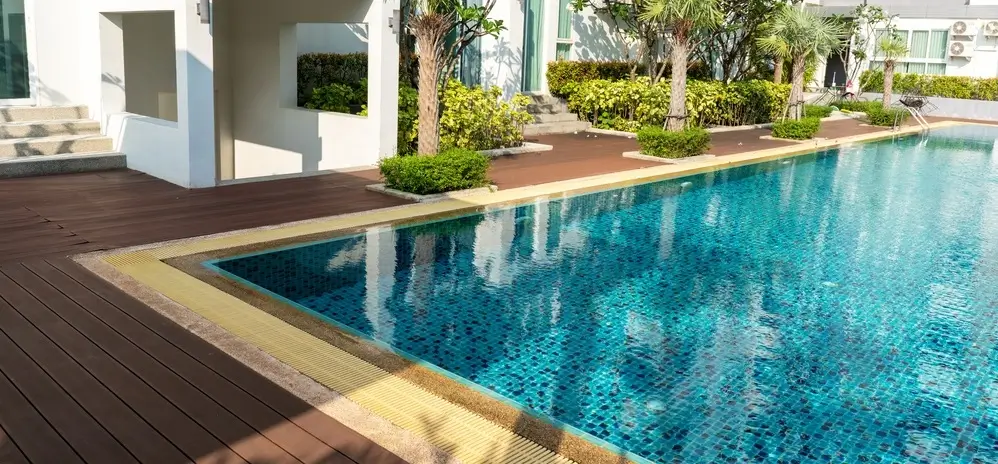 A modern fiberglass pool in Houston with clean water, surrounded by palm trees and lush greenery.