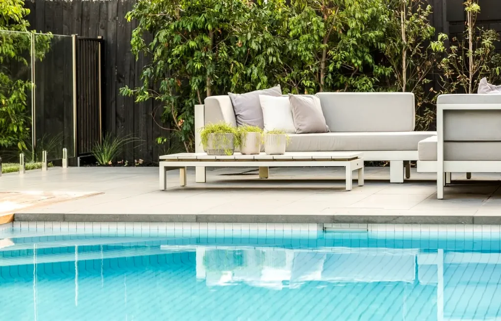 A serene view of a swimming pool with poolside seating and a relaxing atmosphere.