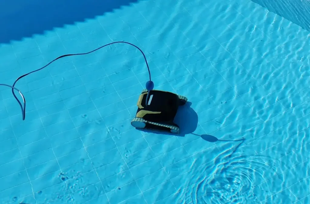 A robotic fiberglass pool vacuum operating underwater in a bright blue swimming pool, connected by a cable for efficient cleaning.