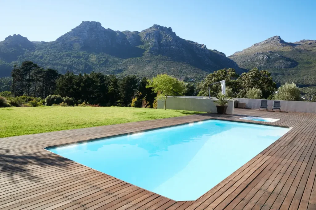 A scenic fiberglass pool in Houston surrounded by wooden decking and overlooking greenery and mountains.