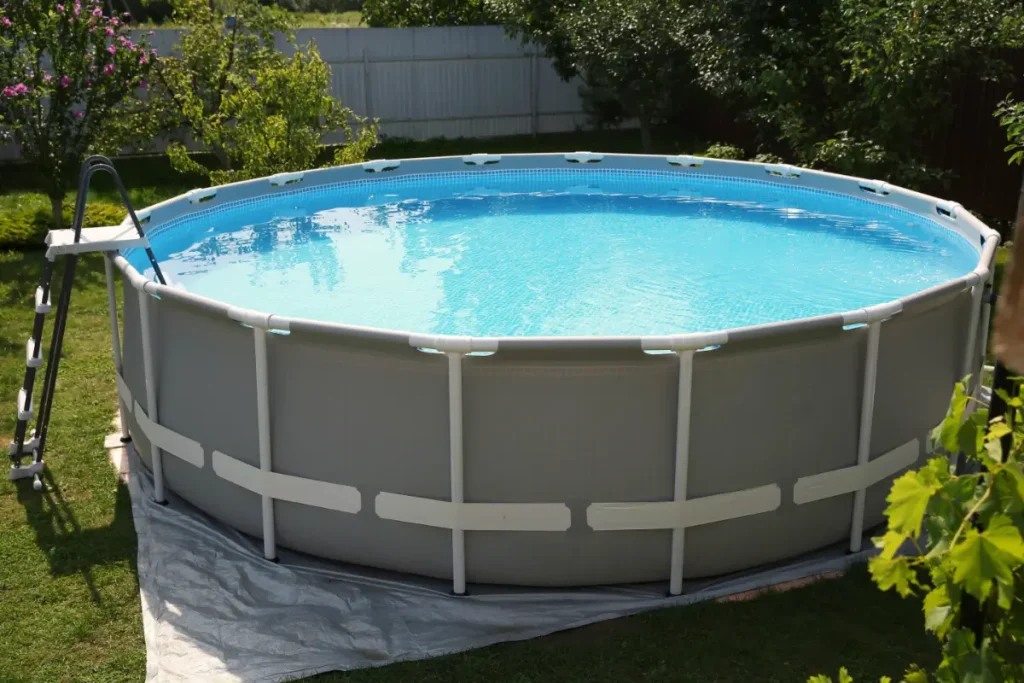 Round above-ground fiberglass pool surrounded by greenery in a backyard garden.