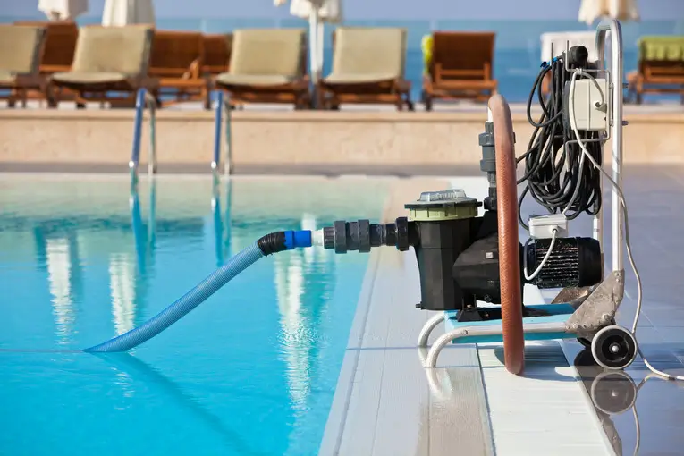 A pool cleaning pump connected to a swimming pool, showcasing efficient pool cleaning services.