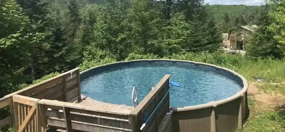 A fiberglass pool installed on a sloped yard, showcasing its adaptability and smooth finish amidst a lush, natural landscape.