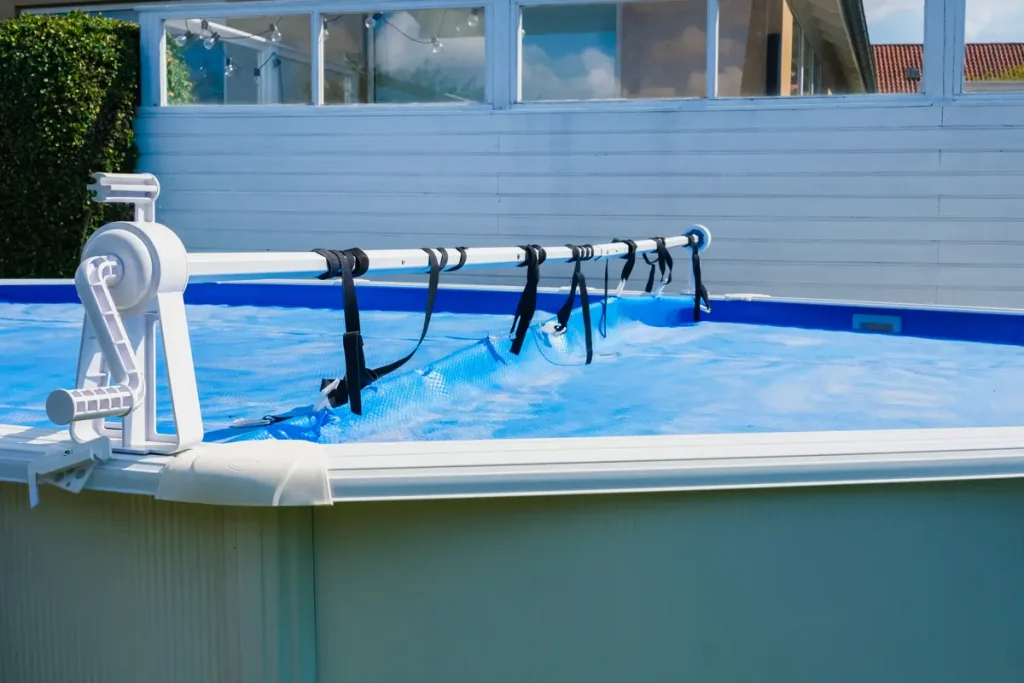 A close-up of an above-ground pool with a blue solar cover on a reel system for safety and energy efficiency.