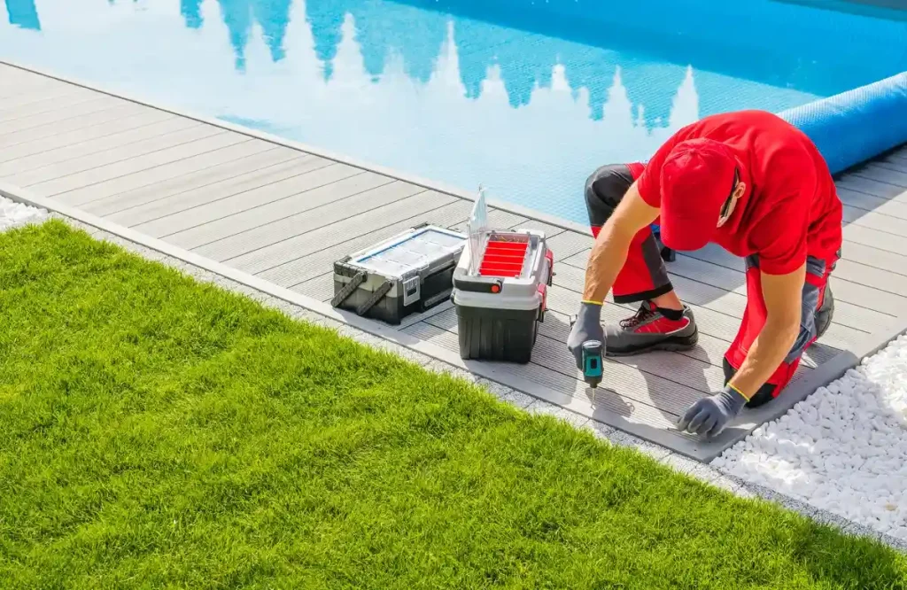 Specialist installing composite decking around an above ground pool with tools and equipment nearby.