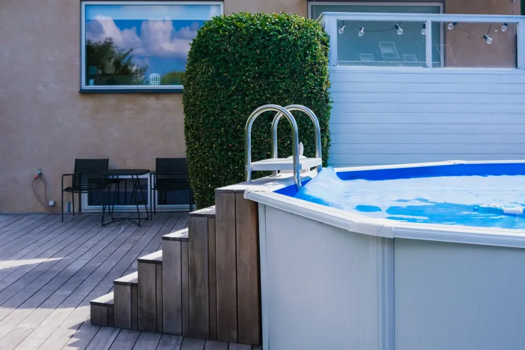 An above-ground pool with wooden steps in a backyard, providing a functional water feature.