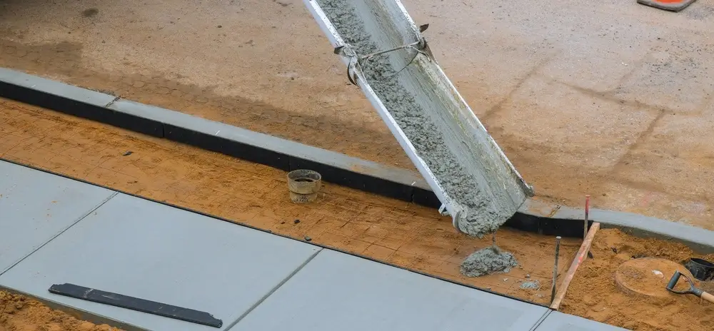 Concrete being poured onto a prepared surface during a pool deck resurfacing project.