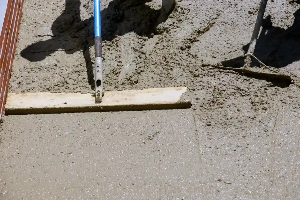 Close-up of tools being used to smooth wet concrete for pool repairs.