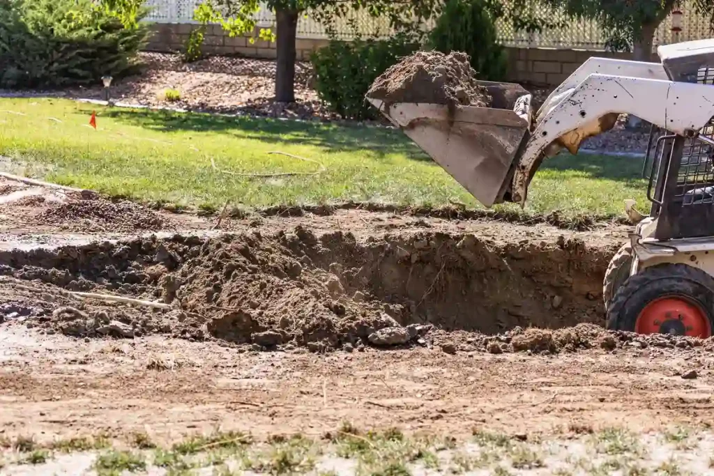 A small bulldozer digging up soil for above ground pool removal, showing excavation cost factors.