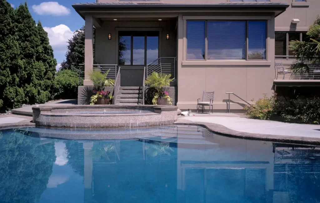 Beautiful backyard featuring a fiberglass pool surrounded by lush greenery and modern architecture.