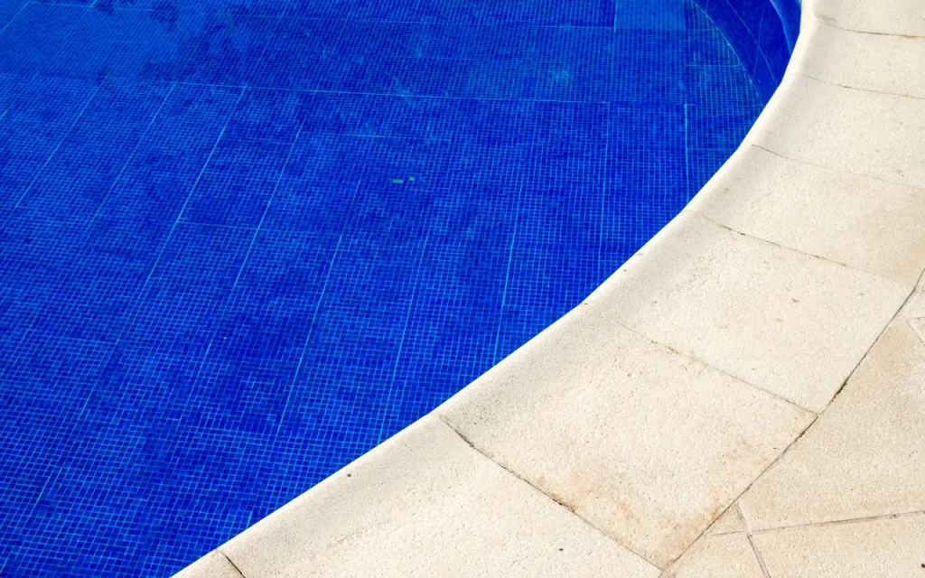 Close-up of a vibrant blue pool with a clean concrete pool deck, designed for comfort and durability.