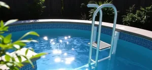 A sturdy above ground pool entry system featuring a curved ladder submerged in clear blue water.