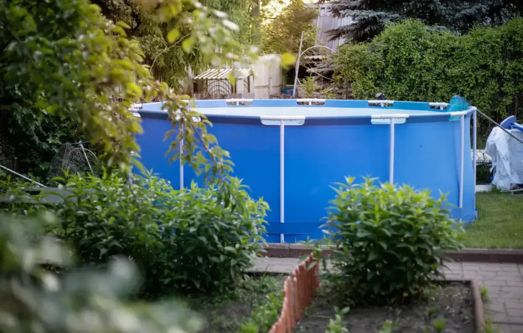 A blue above-ground pool in a country setting, surrounded by potential fence ideas for a rustic and functional look.