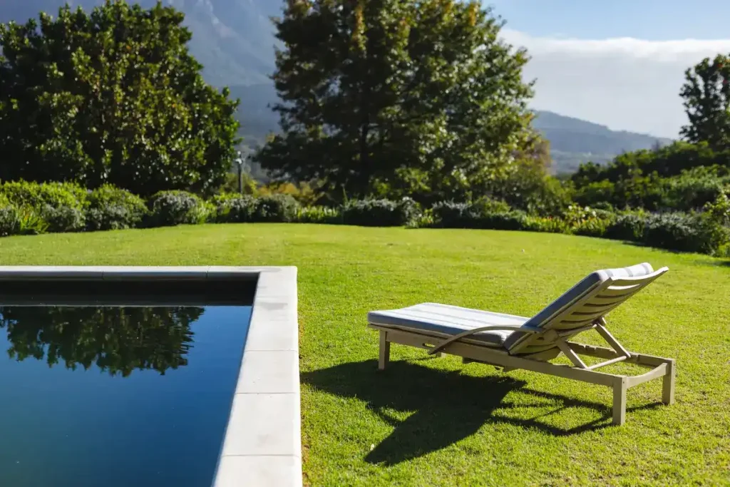 A calm backyard with a pool and a deckchair on green grass, showing the potential of reclaiming space after above ground pool removal.