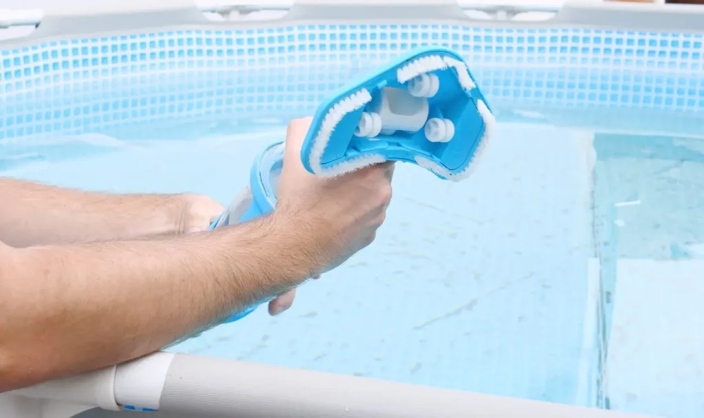 Hands assembling a vacuum cleaner head for cleaning an above-ground swimming pool.