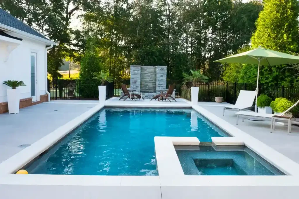 A rectangular fiberglass pool in Ocala with an attached spa, surrounded by a modern patio and lush greenery.