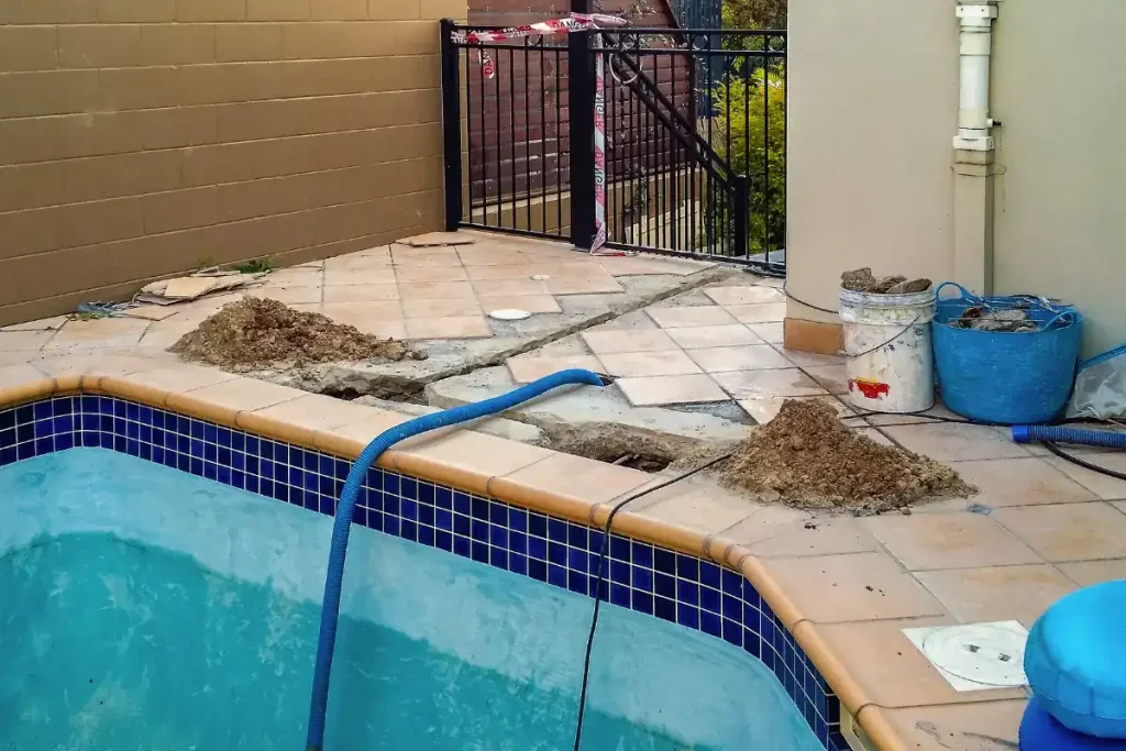 Ongoing patio repair work during fiberglass pool installation in Florida, showing poolside construction details.