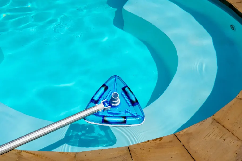 Close-up of a blue triangular vacuum cleaning head used for maintaining a fiberglass pool in Florida.