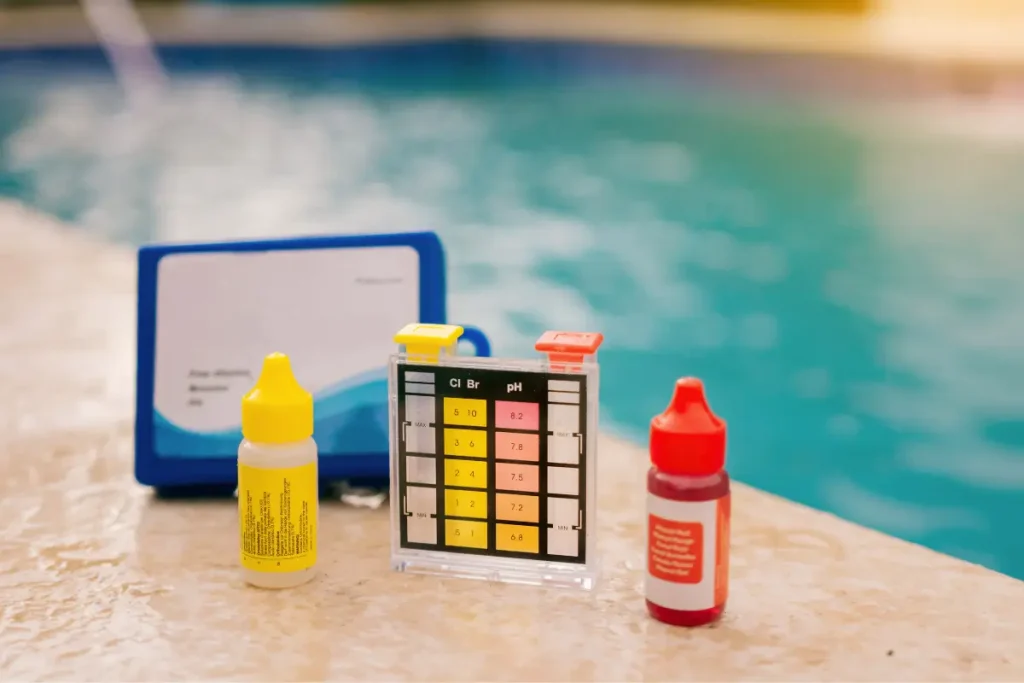 Pool water testing kit placed near a small fiberglass swimming pool.