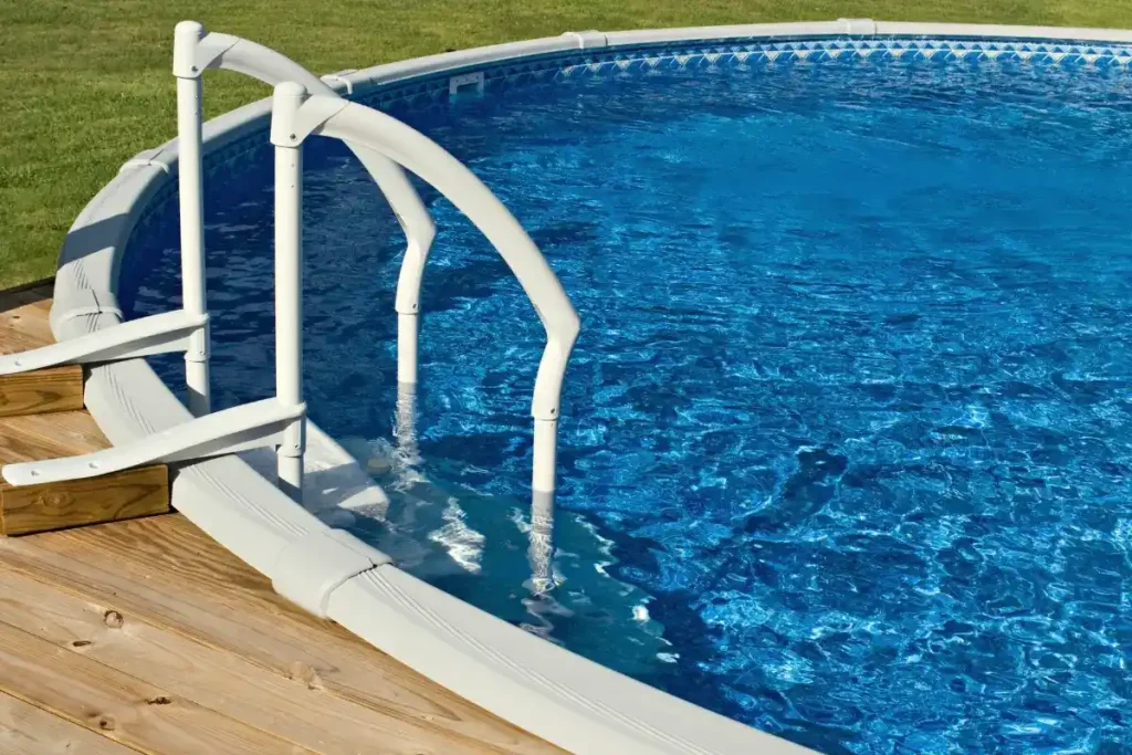 A round above-ground pool with a secure above-ground pool base, surrounded by a wooden deck and featuring clear blue water with a white ladder.