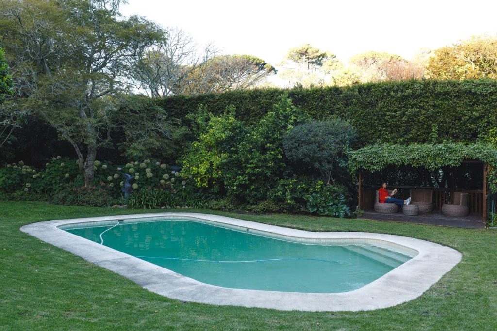 An eco-friendly backyard fiberglass pool near me, surrounded by lush greenery and featuring a cozy gazebo for relaxation