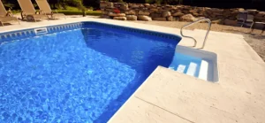 Fiberglass pools in Ocala with a white deck and stone wall backdrop.