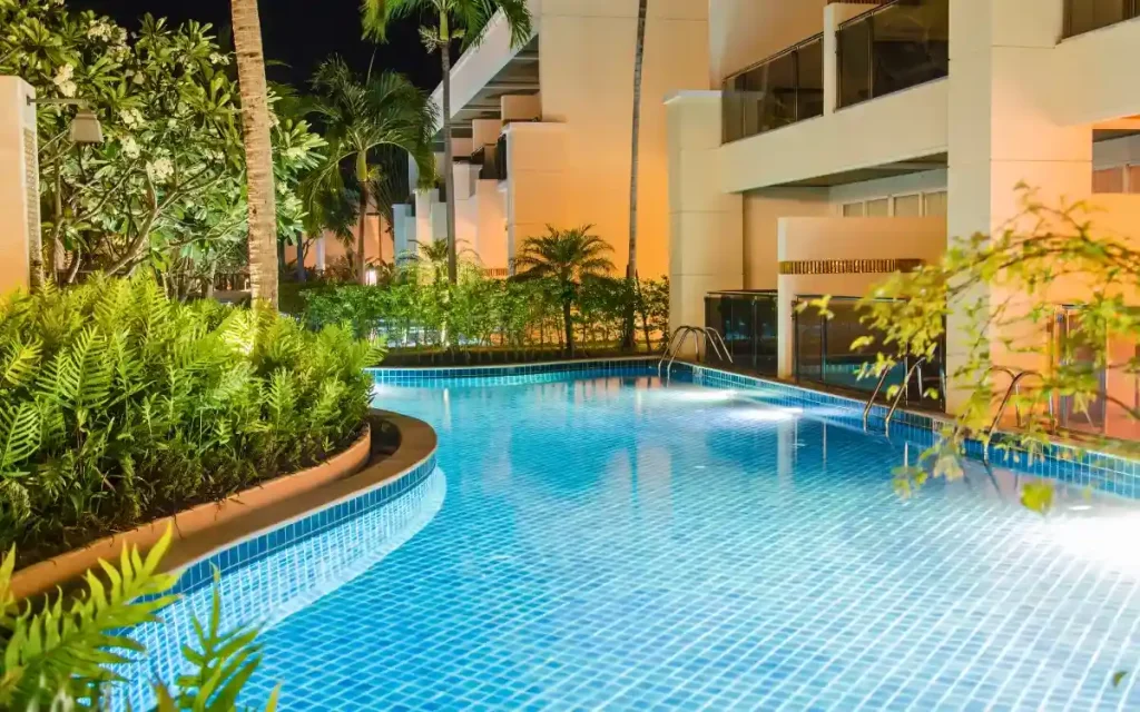 A modern fiberglass swimming pool with blue tile finish, surrounded by lush greenery and elegant architecture.