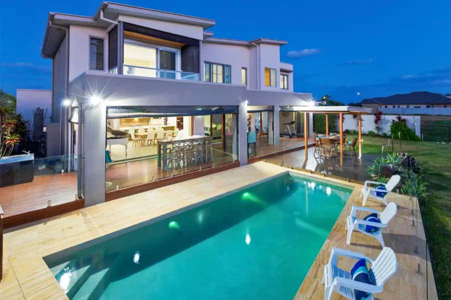 A luxurious backyard pool with modern lighting, surrounded by a stylish patio and outdoor seating.