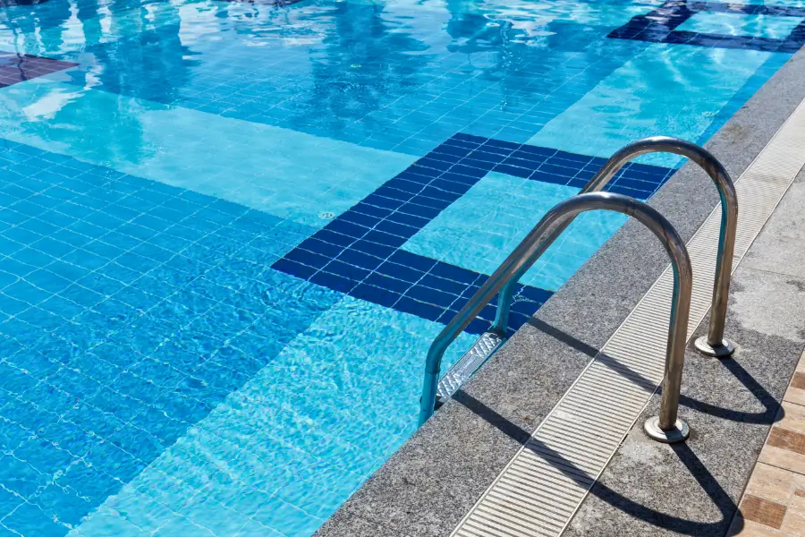 A professionally installed swimming pool with a stainless steel ladder and clean blue water.